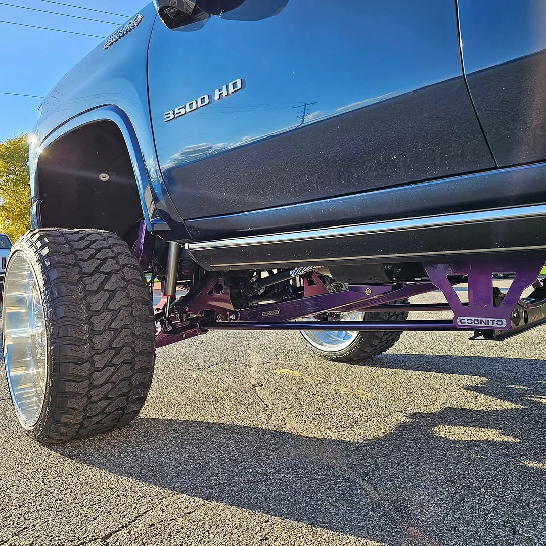 Purple-painted Cognito long-travel arms on lifted 3500 HD